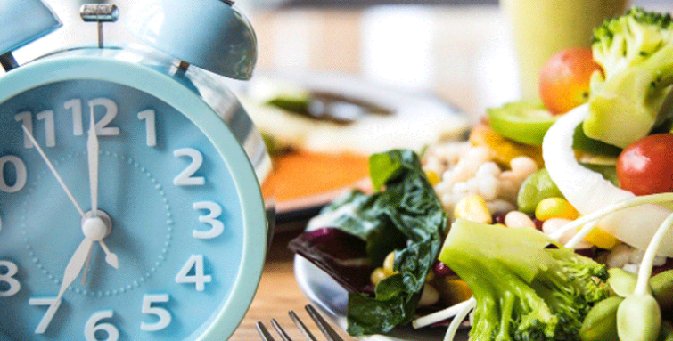 Food on plate with alarm clock next to it